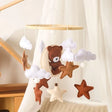 Baby mobile with teddy bear and star decorations hanging.