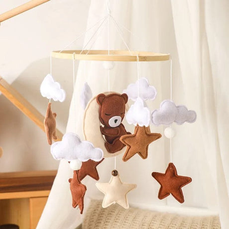 Baby mobile with teddy bear and star decorations hanging.