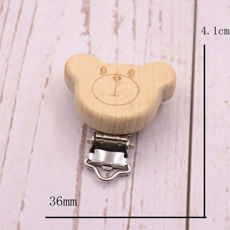 Wooden bear-shaped clip with metal clasp on a light wooden surface, showing measurements.
