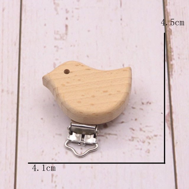 Wooden bird-shaped pacifier clip on a light wooden background with measurements indicated.