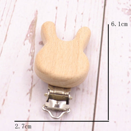 Wooden pacifier clip with measurements on a light background