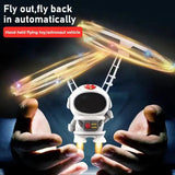 Hand-held flying toy shaped like an astronaut vehicle with glowing effects, held between two hands against a dark background.