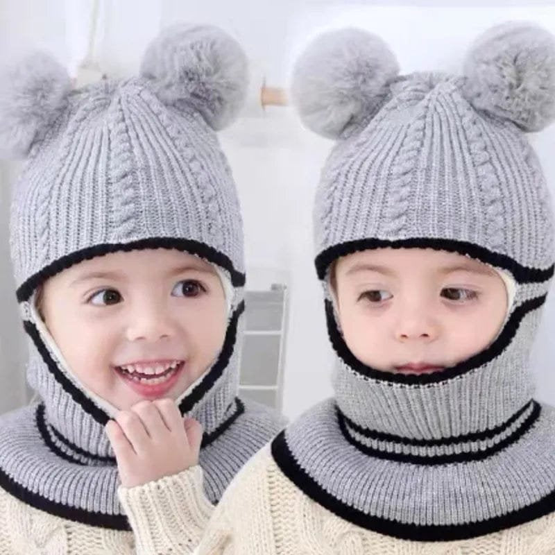 Two children wearing gray knitted hats with pom-poms against a white background