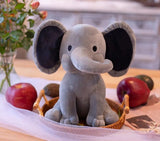 Plush elephant toy on a table with fruits and flowers