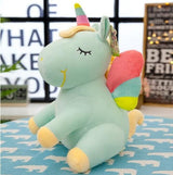 Plush unicorn toy with rainbow mane and tail on a blue blanket