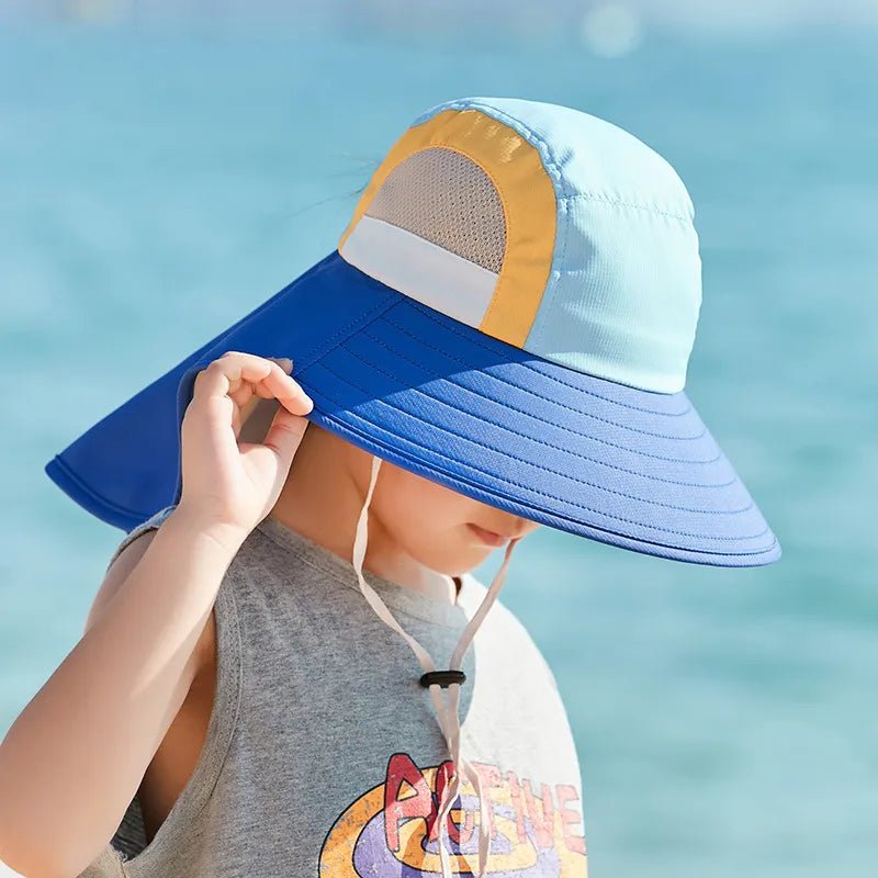 Child wearing a colorful sun hat with a blue brim against a blurred water background