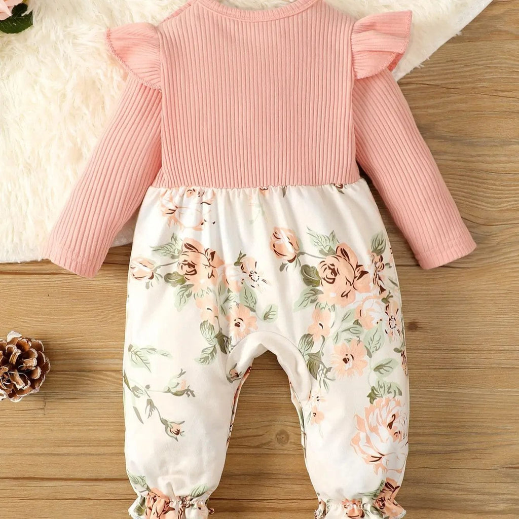Baby outfit with pink top and floral pants on a wooden surface