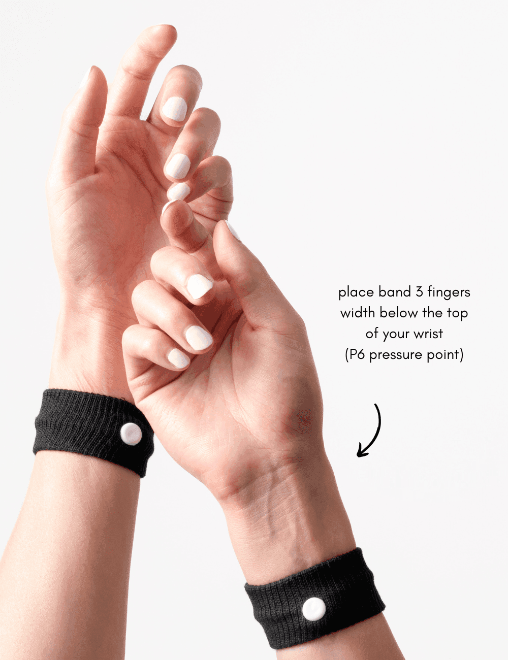 Hands wearing black wristbands with white buttons, demonstrating a pressure point.