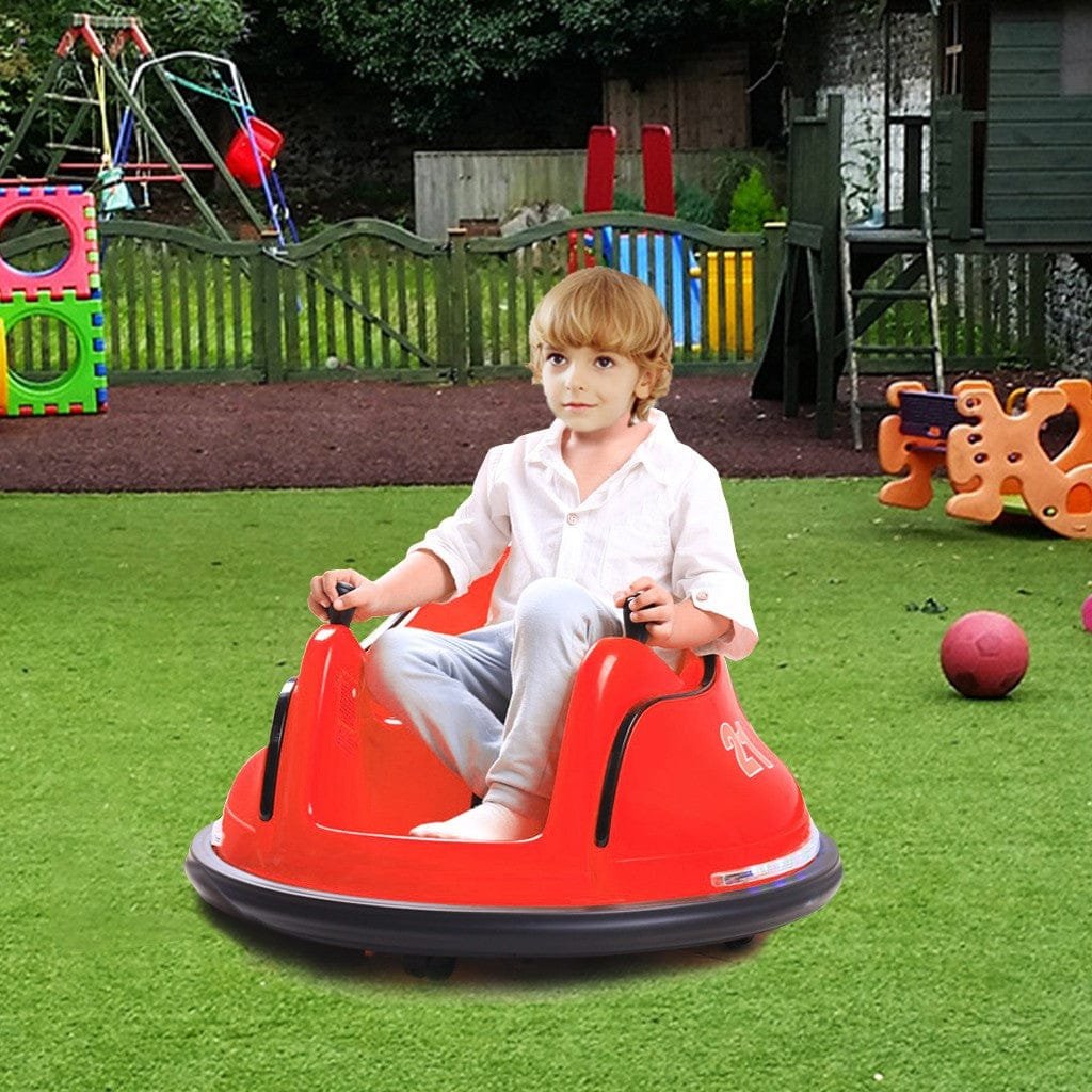 Child sitting in a red bumper car on grass with playground equipment in the background