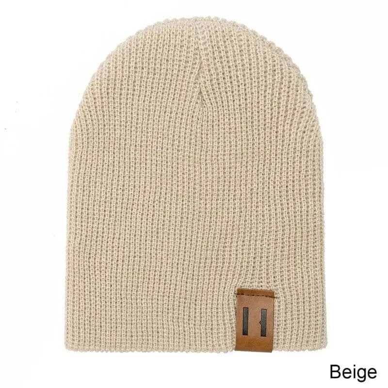 Beige knit beanie with a brown leather patch on a white background