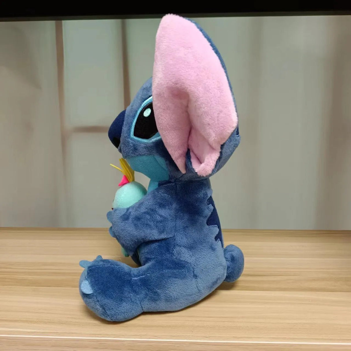 Blue plush toy with pink ears on a wooden surface