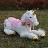Plush unicorn toy with pink dress and gold hooves on grass