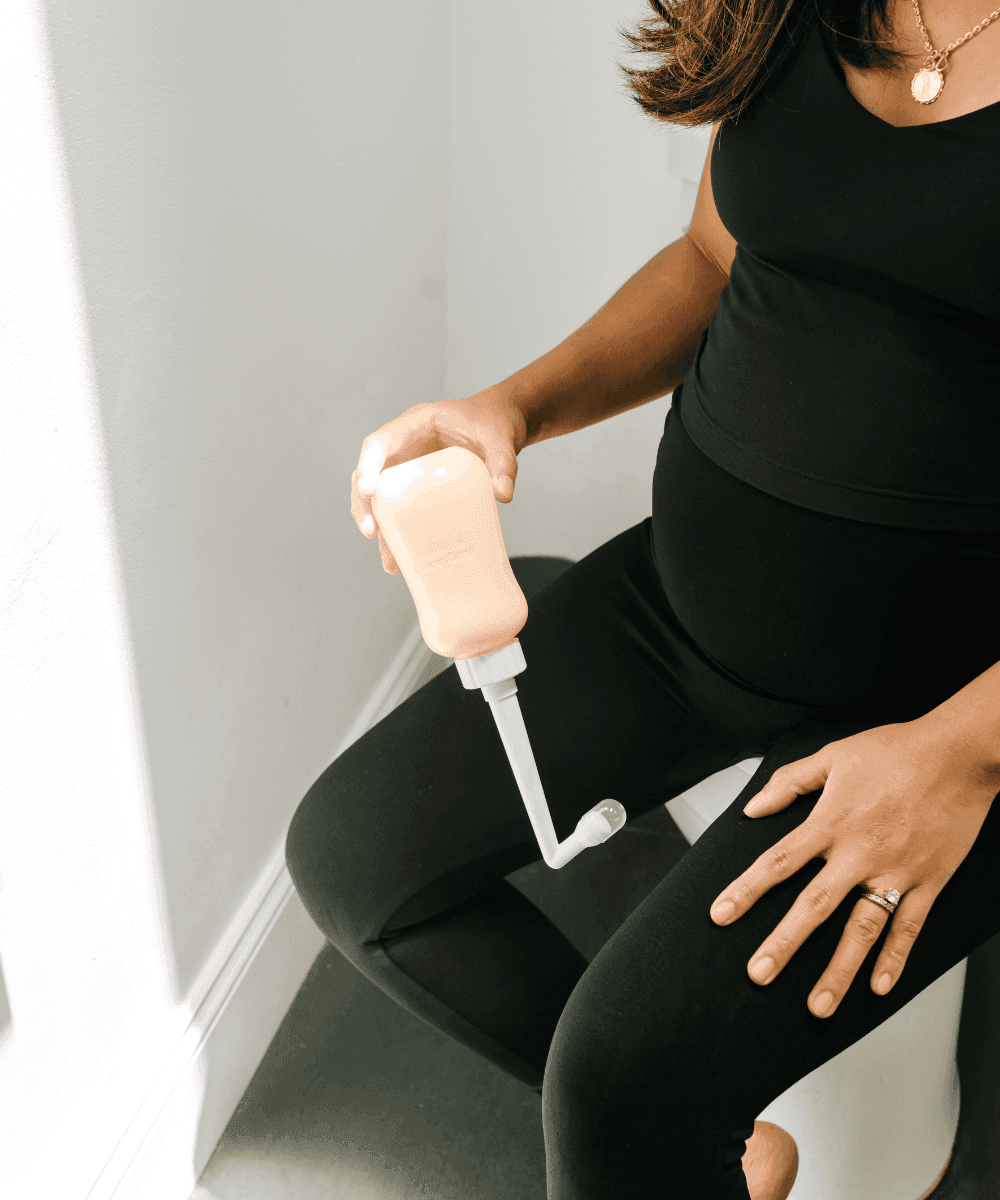 Angled peri bottle in use for easy postpartum cleansing, giving a controlled stream without awkward reaching.