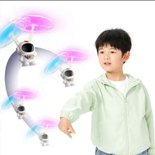 Hand-controlled astronaut drone toy flown by a child outdoors for active backyard play.