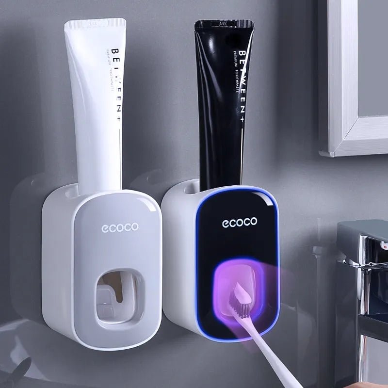 Two ecoco toothpaste dispensers with a black tube of Between toothpaste on a gray background.