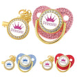 Decorative pacifiers with 'Prince' and 'Princess' text and crowns, in gold, pink, blue, and red.