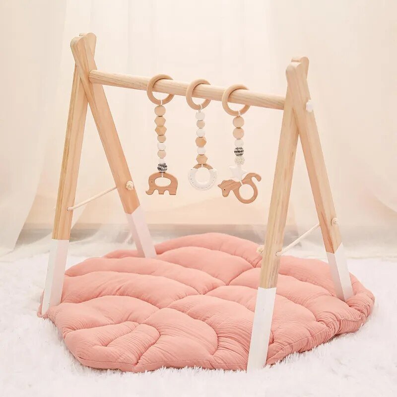 Wooden baby gym with pink mat and hanging toys on a white background