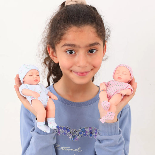 Young girl holding two baby dolls against a plain background