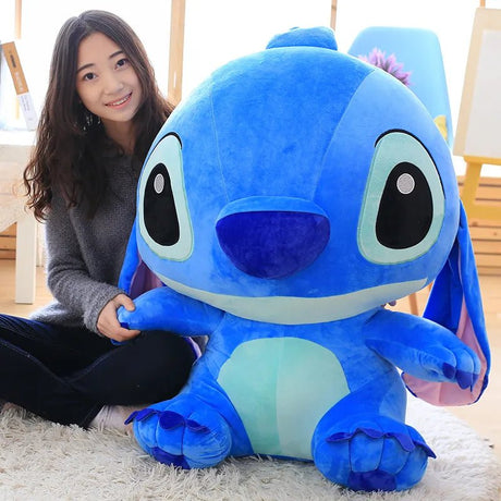 Person holding a large blue plush toy resembling a character from an animated movie.