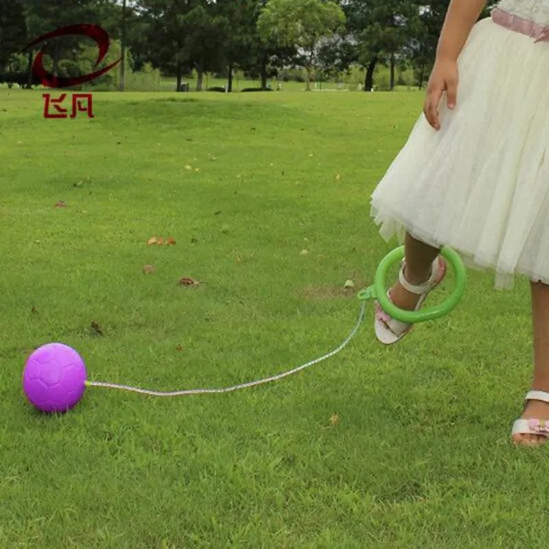 Person in a white dress with a green hoop and purple ball on grass