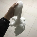 White plush toy resembling a swan held by a hand on a tiled floor.