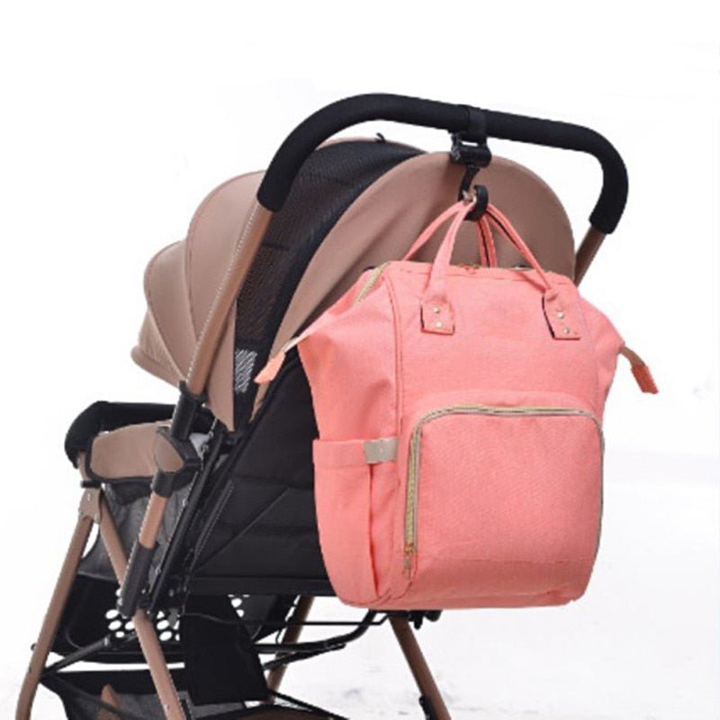 Baby Bag Stroller Hooks non-slip hanger clips holding a pink diaper bag for organised strolls, travel, and shopping trips.