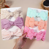 Set of colorful fabric bows on a white box with a hand holding it.