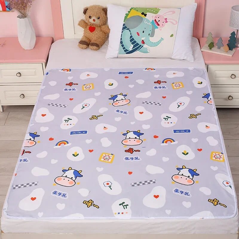 Children's bed with a cartoon-patterned mattress cover, teddy bear, and decorative pillows.