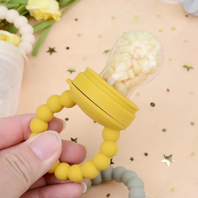 Yellow Baby Fruit Feeder Pacifier held in hand, an easy-grip teether for soothing sore gums during weaning.
