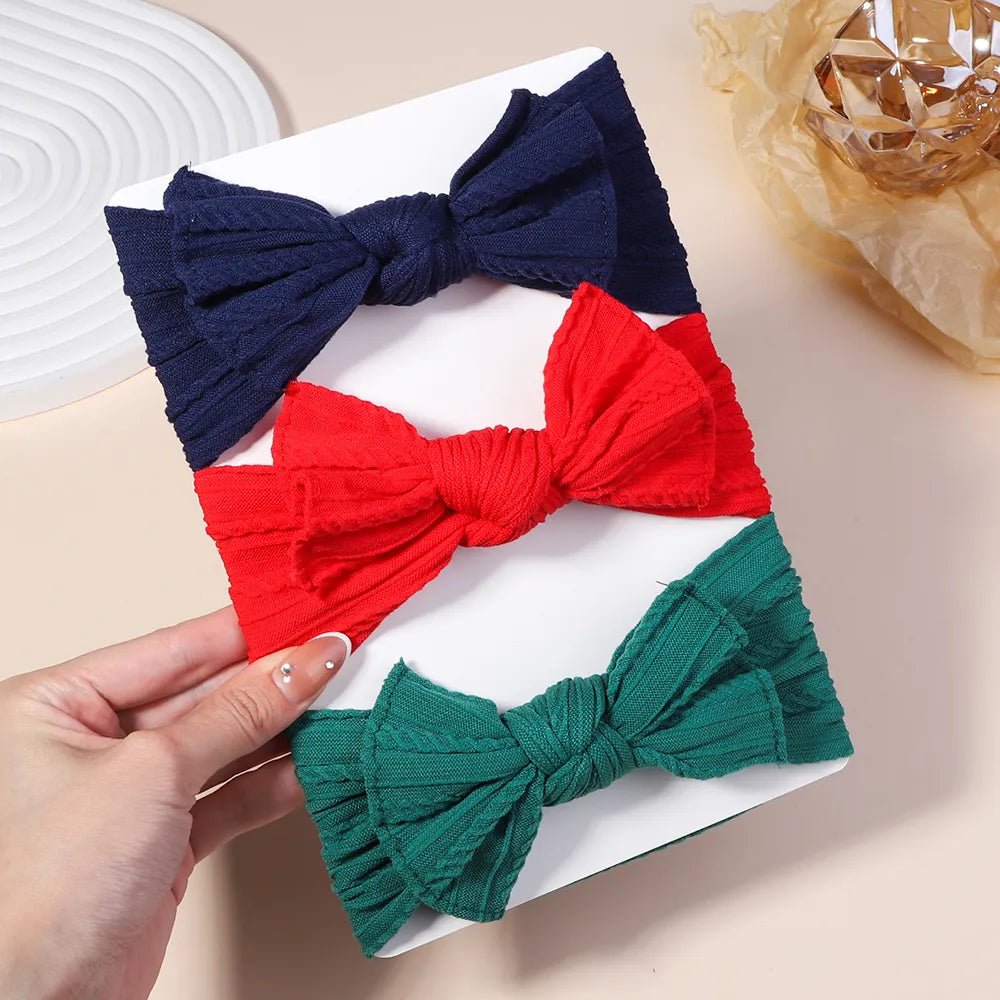 Three colorful hair bows held by a hand