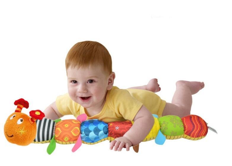 Baby lying on the plush caterpillar rattle toy, a soft musical companion for tummy time and cot play.