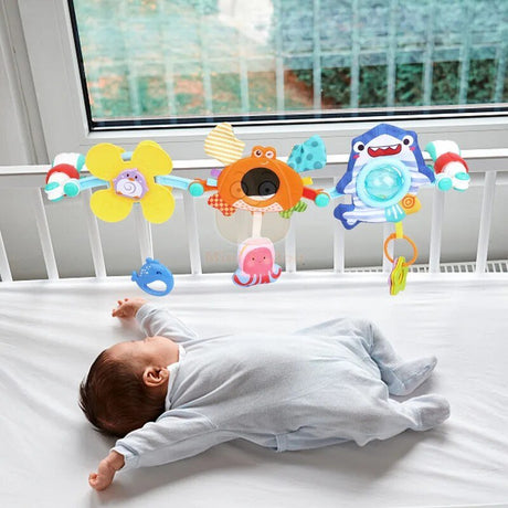 Baby lying in a crib with colorful baby toys hanging above