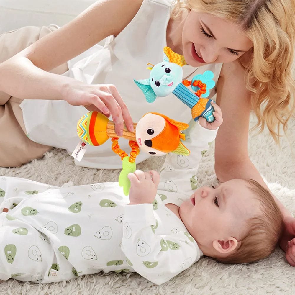 Woman playing with a baby and colorful baby toys on a soft surface