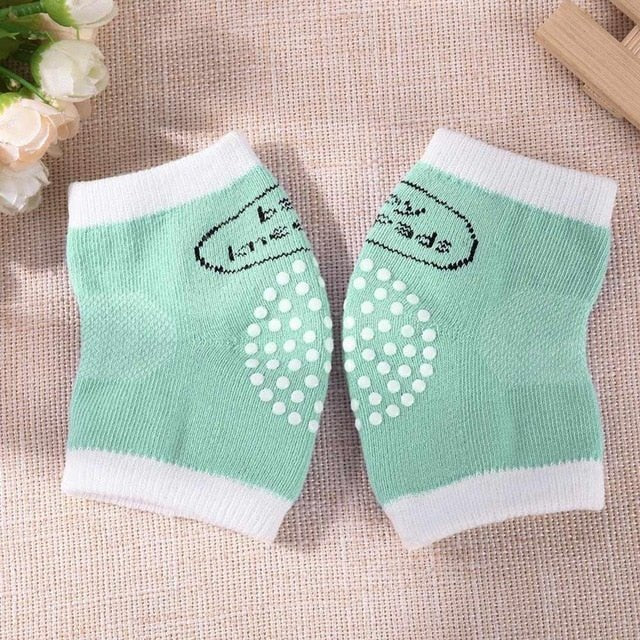 Pair of green baby socks with white polka dots and text.