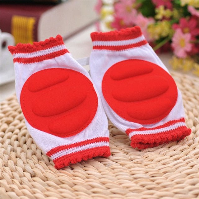 Pair of red and white knee pads on a woven surface.