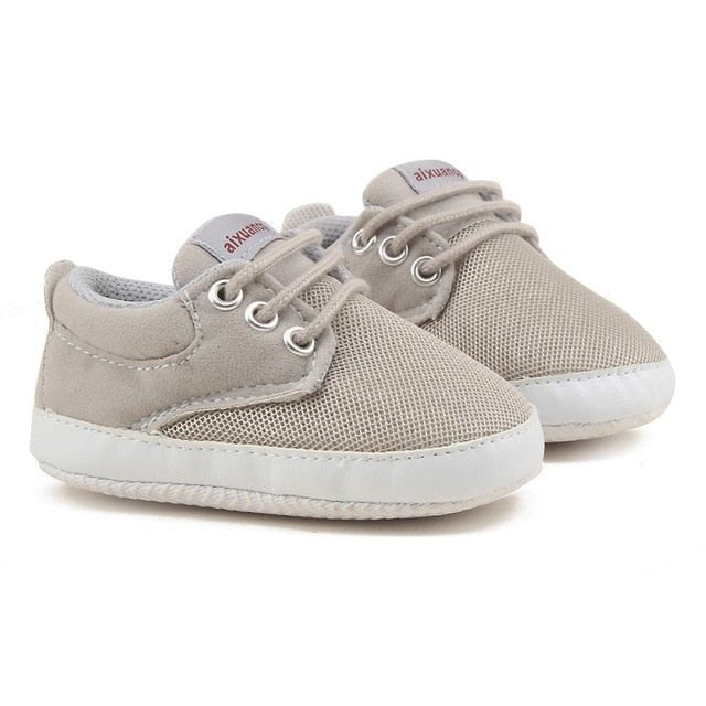 Pair of gray baby sneakers with white soles 