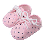 Pink baby shoes with white laces and paw print pattern 