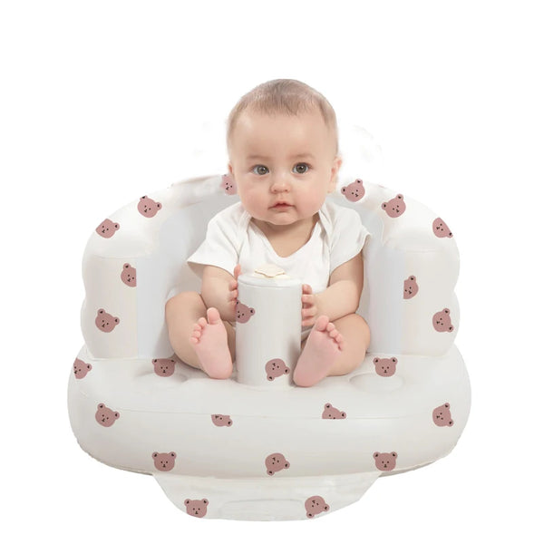 Baby sitting in an inflatable seat with teddy bear pattern for supported floor play.