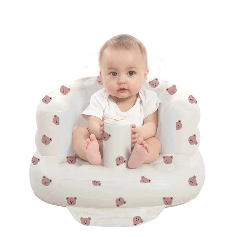 Baby sitting in a white inflatable seat with bear cushion pattern for supported sitting.