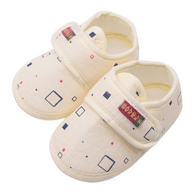 Pair of cream-colored baby shoes with a geometric pattern 