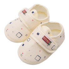 Pair of cream-colored baby shoes with a geometric pattern 