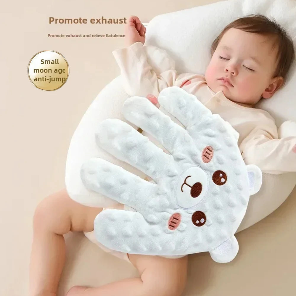 Baby resting with a blue bear-face palm pillow on the tummy