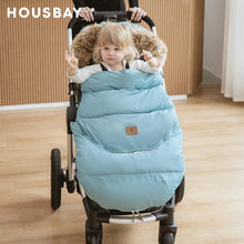 Child seated in a stroller wrapped in the blue winter footmuff, keeping infants insulated during cold-weather outings.