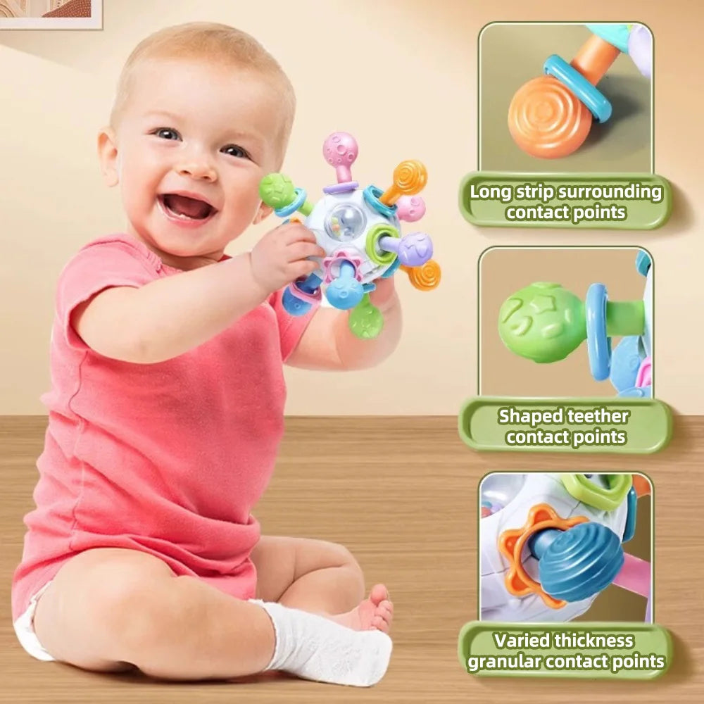 Smiling baby sitting and holding a colorful teether grasping ball