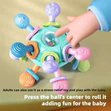 Finger pressing the center of a teal teether and grasping ball with colorful knobs