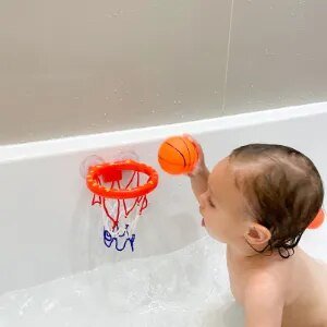 Baby playing with the whale bath basketball set in the tub for splashy bath time fun.