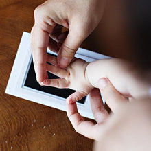 Adult holding a newborn hand before taking a keepsake print with the non-toxic imprint kit.