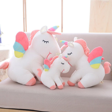 Set of unicorn-shaped pillows with colorful accents on a light-colored couch.