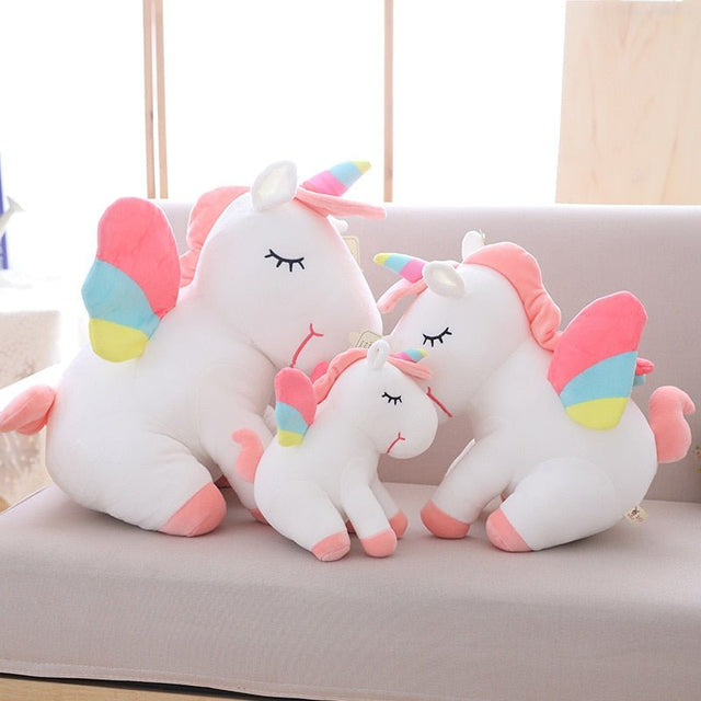 Set of unicorn-shaped pillows with colorful accents on a light-colored couch.
