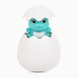 Toy frog emerging from a white egg on a white background